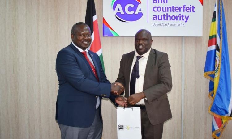 NACADA CEO Dr. Anthony Omerikwa, MBS, hands a gift hamper to the CEO of the Anti-Counterfeit Authority Dr. Robbi Mbugua